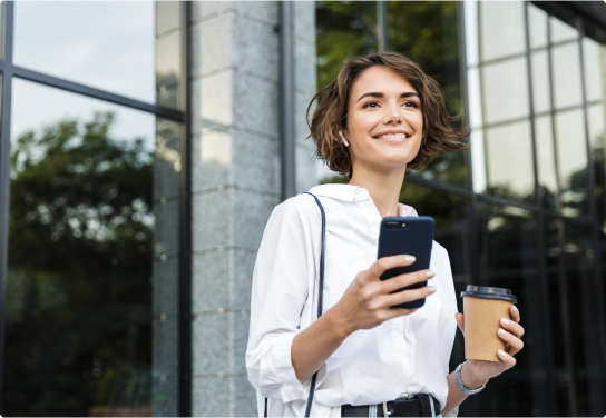 Case Study - Manukau Institute of Technology - Image Woman outside a office building holding a mobile phone and a coffee