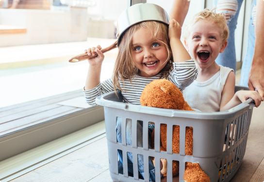 Business - Sponsorship - Variety the Children’s Charity Photo of two children smiling playing in a washing basket with the young girl holding a pot on her head