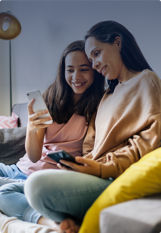 Mother and daughter sitting on the couch on a mobile phone