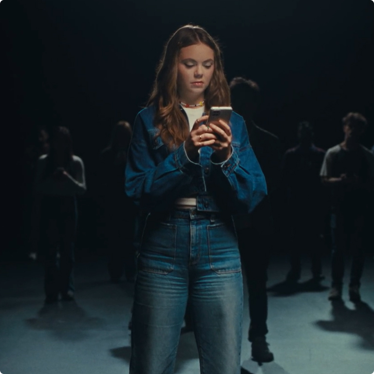 Girl standing in a dark room with people around her covered in darkness.