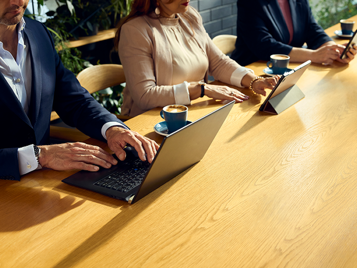 People sitting at a desk on laptops and phones drinking coffee