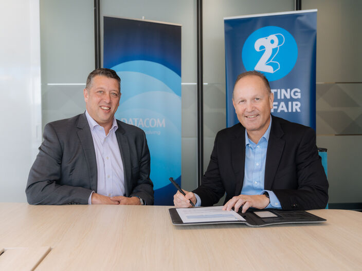 Andfrew Fairgray from 2degrees and Justin Gray from Datacom sit at a table signing the partnership agreement